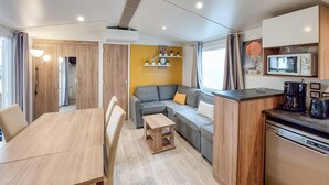 Un espace de vie compact comprenant un coin repas, un canapé, une cuisine équipée d’un four à micro-ondes et une petite table.