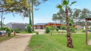 Un bâtiment doté d’un espace extérieur abrité, entouré d’une pelouse verdoyante et d’arbres.