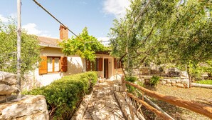 A stone pathway leading to a rustic house with a chimney, surrounded by greenery and a stone wall. - Beach front home in Novalja with house sea view (Novalja)