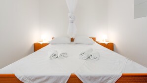 A neatly made bed with white linens, two bedside lamps, and a white canopy. - Beach front home in Novalja with house sea view (Novalja)