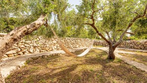 A hammock between two olive trees in a stone-walled garden. - Beach front home in Novalja with house sea view (Novalja)