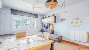 Un salon moderne comprenant un coin repas, un ventilateur de plafond, une horloge murale et une fenêtre donnant sur l’extérieur.
