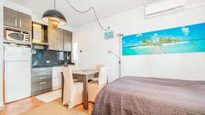 Une pièce compacte comprenant un coin cuisine, un espace repas et un lit.