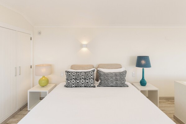 A bedroom with a bed, two bedside tables, a lamp, and a wardrobe. - Casa Por do Sal (Lagos)