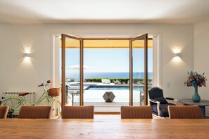 A dining area with a view of the sea, a pool, and a bicycle. - Casa Por do Sal (Lagos)