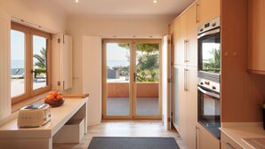 Eine Küche mit Meerblick, Holzschränke, ein Toaster und eine Schüssel Orangen.