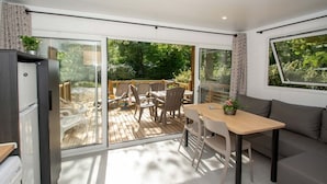Un intérieur moderne avec une porte-fenêtre coulissante donnant sur une terrasse, un canapé, une table et un réfrigérateur.