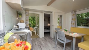 Une cuisine compacte équipée d’une cuisinière à gaz, un coin repas avec une table et des chaises, et un petit coin salon avec un canapé.