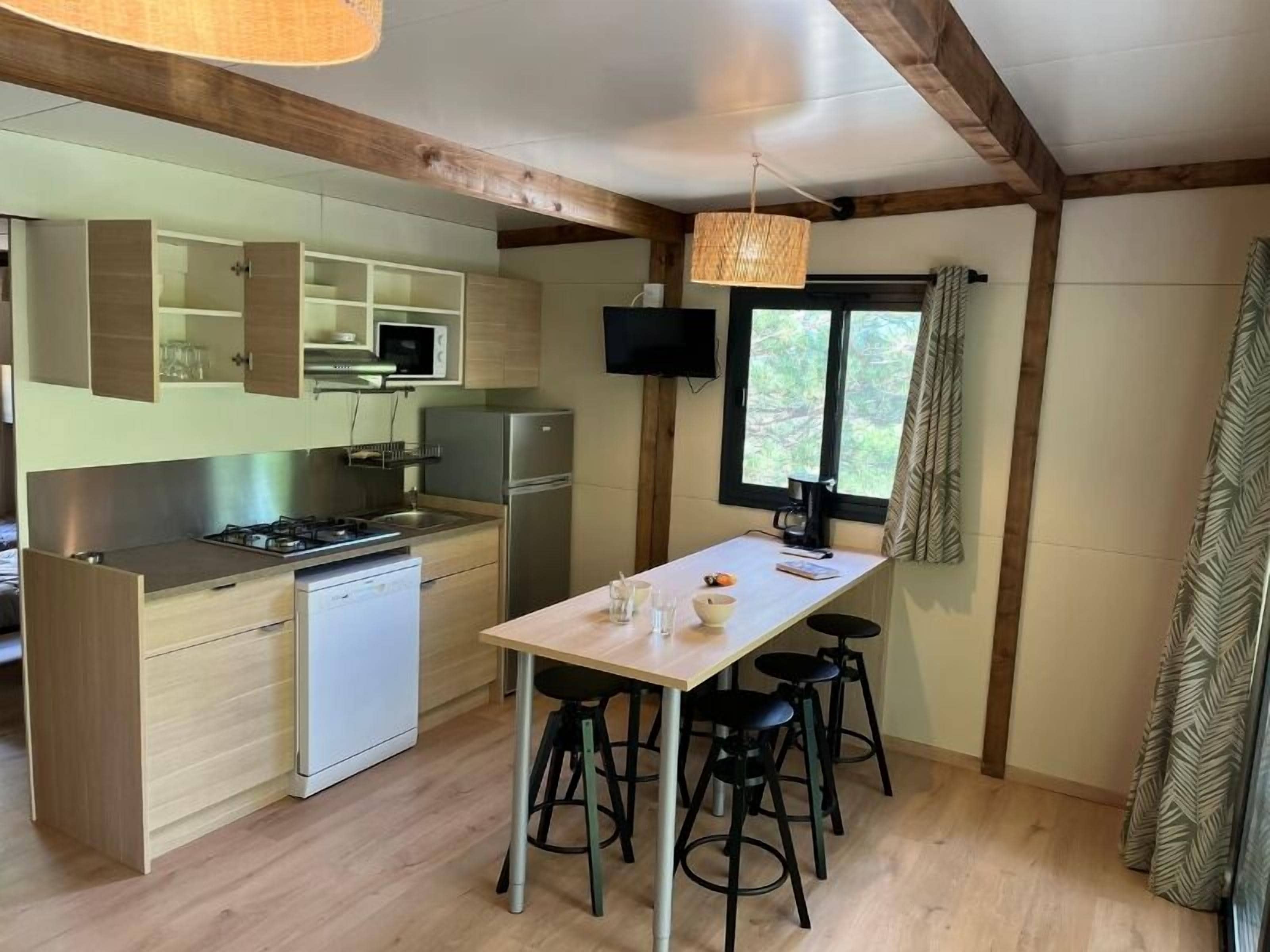 A compact kitchen with modern appliances, a central island with stools, and a large window providing natural light.