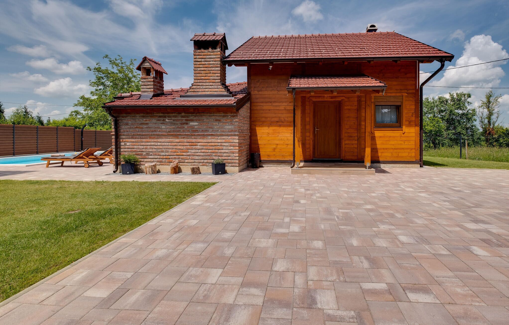 Una casa de madera con chimenea de ladrillo, puerta de madera y un patio empedrado.