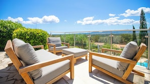 Une terrasse dotée de chaises longues en bois et d’une balustrade en verre, offrant une vue panoramique sur un paysage magnifique.