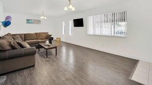 A spacious living room with a brown leather sofa, a coffee table, and a TV mounted on the wall. - 4 beds 2 baths in Las Vegas
 (Las Vegas)