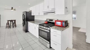 A modern kitchen with white cabinets, a gas stove, a refrigerator, and a microwave. - 4 beds 2 baths in Las Vegas
 (Las Vegas)