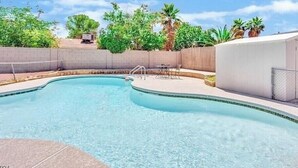 A swimming pool with a curved edge, surrounded by a fence and palm trees. - 4 beds 2 baths in Las Vegas
 (Las Vegas)