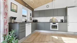 Eine moderne Küche mit grauen Schränken, einem eingebauten Backofen und einer Kaffeemaschine.