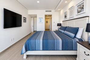 Ein Schlafzimmer mit einem Bett, einem flachbildfernseher an der Wand und einem Nachttisch mit Lampe.