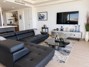 A modern living room with a sectional sofa, a coffee table, a flat-screen TV, and a decorative console.