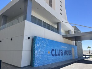 A modern building with a large blue sign advertising a club house.