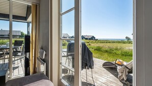 Una habitación con un ventanal grande que da a una terraza y un área verde con casas a lo lejos.