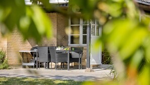An outdoor patio with a table and chairs, a grill, and a brick wall. - 3 bedroom awesome home in Brenderup Fyn (Brenderup Fyn)