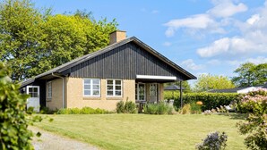 A single-story house with a sloped roof, a brick facade, and a small porch with a table and chairs. - 3 bedroom awesome home in Brenderup Fyn (Brenderup Fyn)