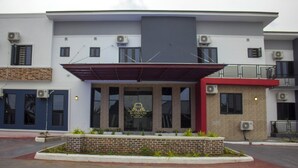 A modern building with a prominent entrance, air conditioning units, and a brick planter with plants. - P.I.O Suites (Abraka)