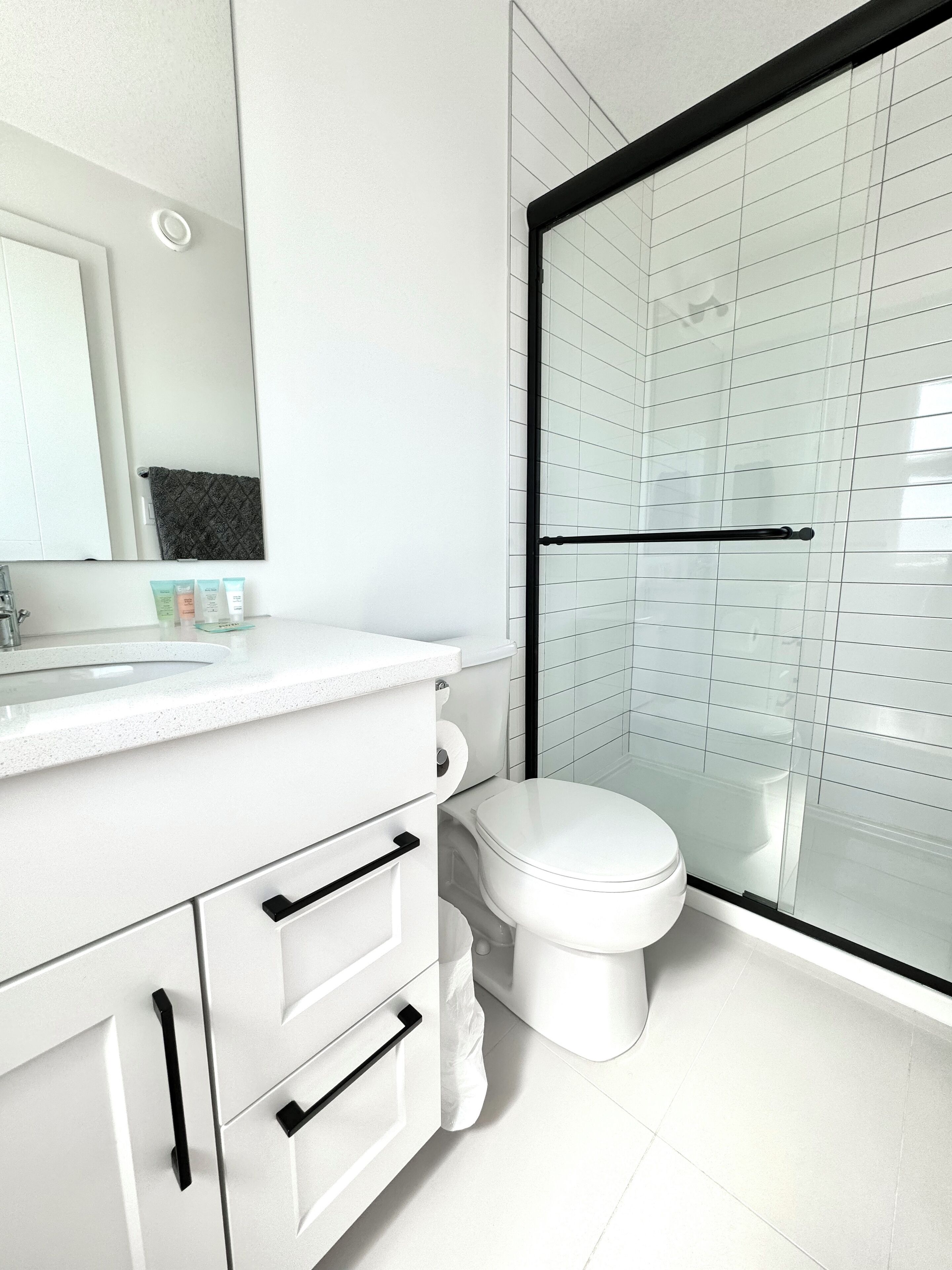Une salle de bain moderne avec un meuble-lavabo blanc, des toilettes et une douche à parois de verre.