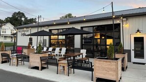 An outdoor seating area with tables and chairs, a sign for 'MillerSport Coffee', and a building with large windows. - !Newly Upgraded! Hot Tub-Game Room-Dock-Fire Pits (Millersport)