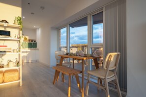 Enjoy a city view from the large window in this room, which features a dining table, bench, and bookshelf.