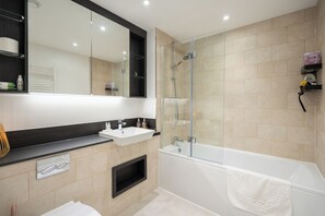 Enjoy a refreshing shower in the sleek bathroom with a dual sink vanity and glass-enclosed shower area.