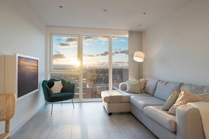 Enjoy a panoramic city view from the large window in this stylish living room, featuring a comfortable sofa and a chic armchair.