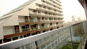 A modern multi-story hotel with balconies, large windows, and a view of the cityscape. - Immaculate Beauty Gem Location Pools Gym (Accra)