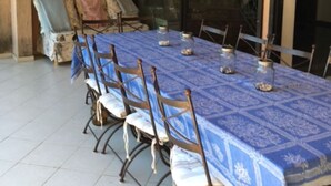 Zona pranzo con un tavolo lungo ricoperto da una tovaglia blu, circondato da sedie in metallo.
