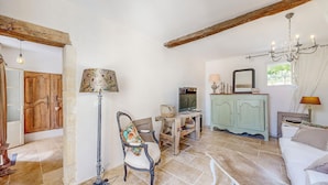 A rustic room with exposed wooden beams, a vintage television, a wooden cabinet, a patterned armchair, and a chandelier. - Nice home in Port-Sainte-Foy-Pontch (Port-Sainte-Foy-Pontch)