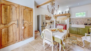A kitchen with a dining area, featuring a chandelier, wooden cabinets, and a tiled backsplash. - Nice home in Port-Sainte-Foy-Pontch (Port-Sainte-Foy-Pontch)