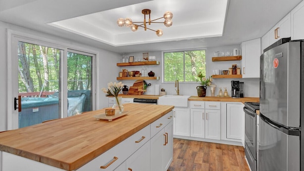 Eine moderne Küche mit weißen Schränken, einer Holz Arbeitsplatte, einem Edelstahlkühlschrank und einem Oberlicht.