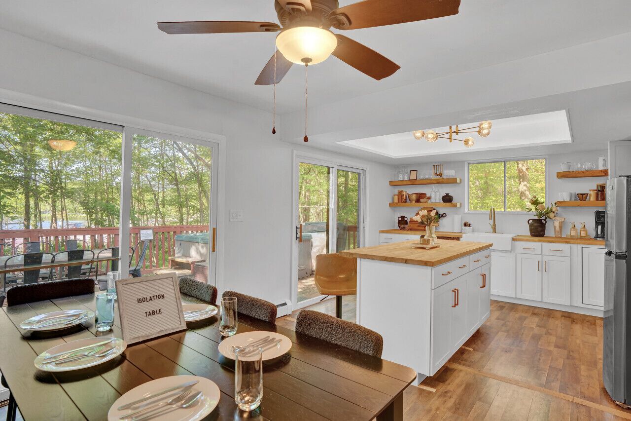 A modern kitchen with white cabinets, a wooden island, and a ceiling fan.