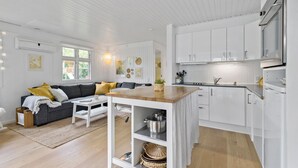 Een moderne keuken met witte kastjes, een houten eettafel en een geïntegreerd kookeiland met planken.