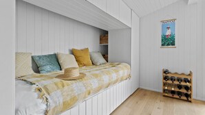 Een slaapkamer met een bed, kussens, een hoed, een poster en een wijnrek.