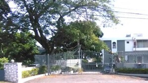 A gated residential area with a building that has a flat roof and multiple windows.
