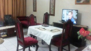 A dining area with a table set for four, chairs, a television, and framed pictures on the wall.