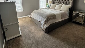 Een slaapkamer met een groot bed, een plafondventilator en een dressoir.