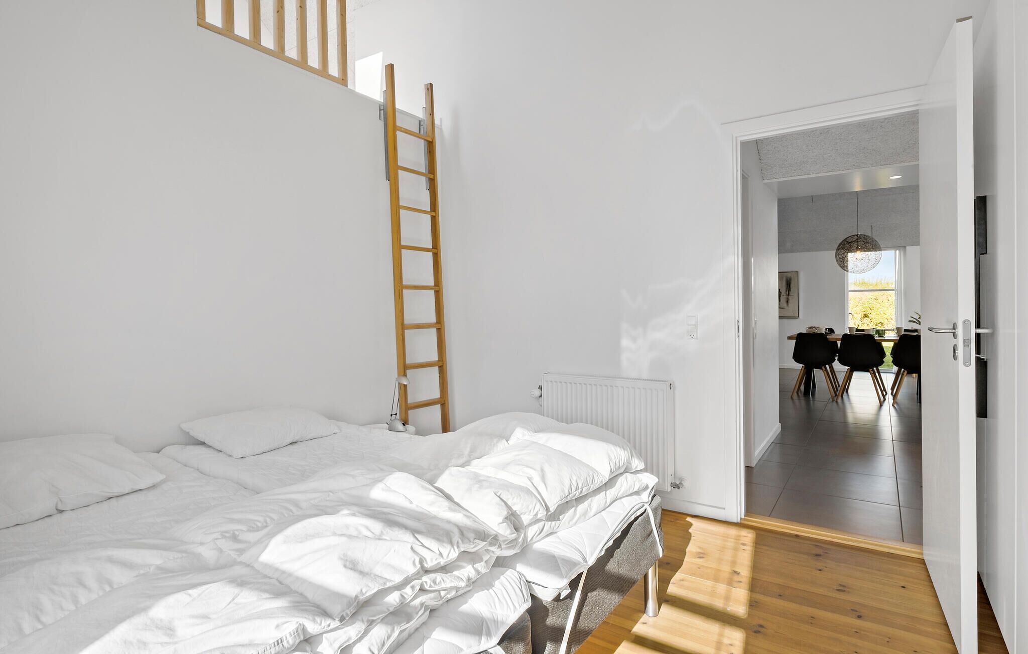 Un dormitorio con cama, una escalera, un radiador y vistas a un comedor.