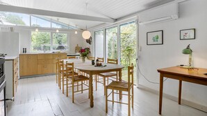 Une cuisine moderne avec un coin repas, de grandes fenêtres et une vue sur la verdure.