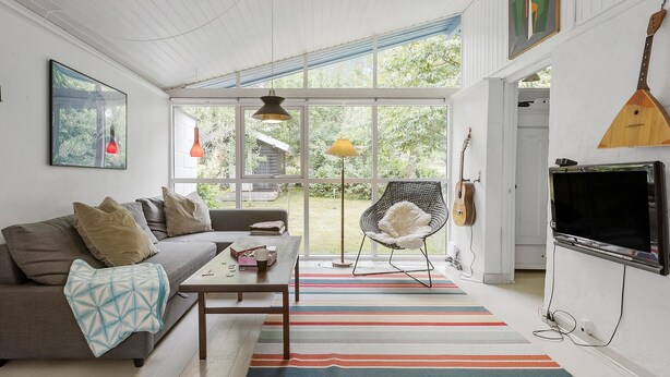 Un salon moderne avec un canapé, une table basse, un tapis à rayures et un téléviseur.
