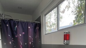Une salle de bain équipée de toilettes, d’un lavabo et d’un rideau de douche orné de motifs floraux.