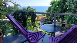 Un balcon donnant sur la mer, entouré d’une végétation luxuriante.