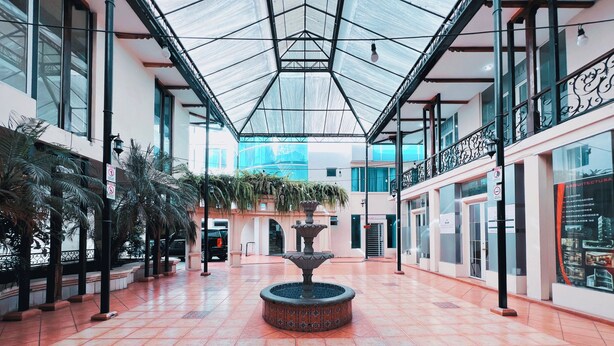 A spacious atrium with a central fountain, large windows, and a glass ceiling. - Departamento Centrico en Loja (Loja)