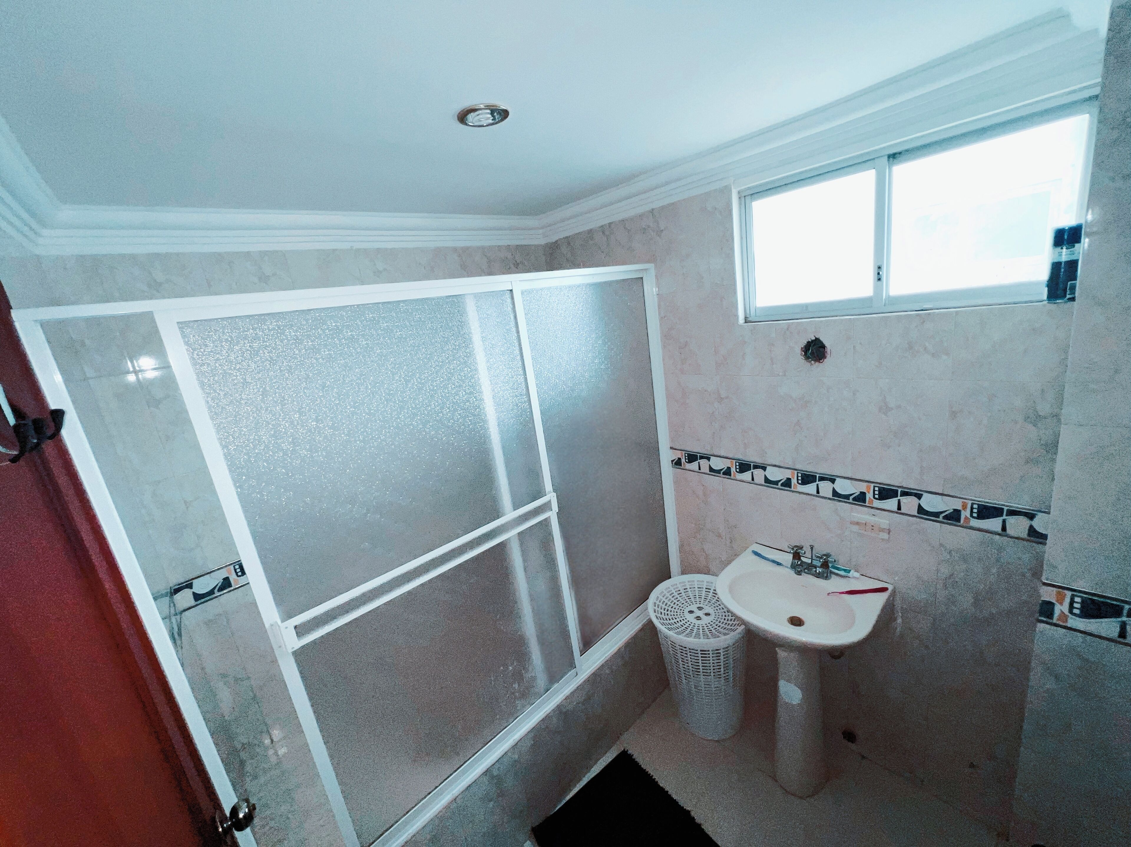 A bathroom with a shower, a sink, and a window.