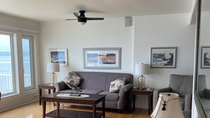 A spacious living room with a wooden floor, a grey sofa, a coffee table, and a ceiling fan. - Sunset Retreat Awaits (Big Pond)
